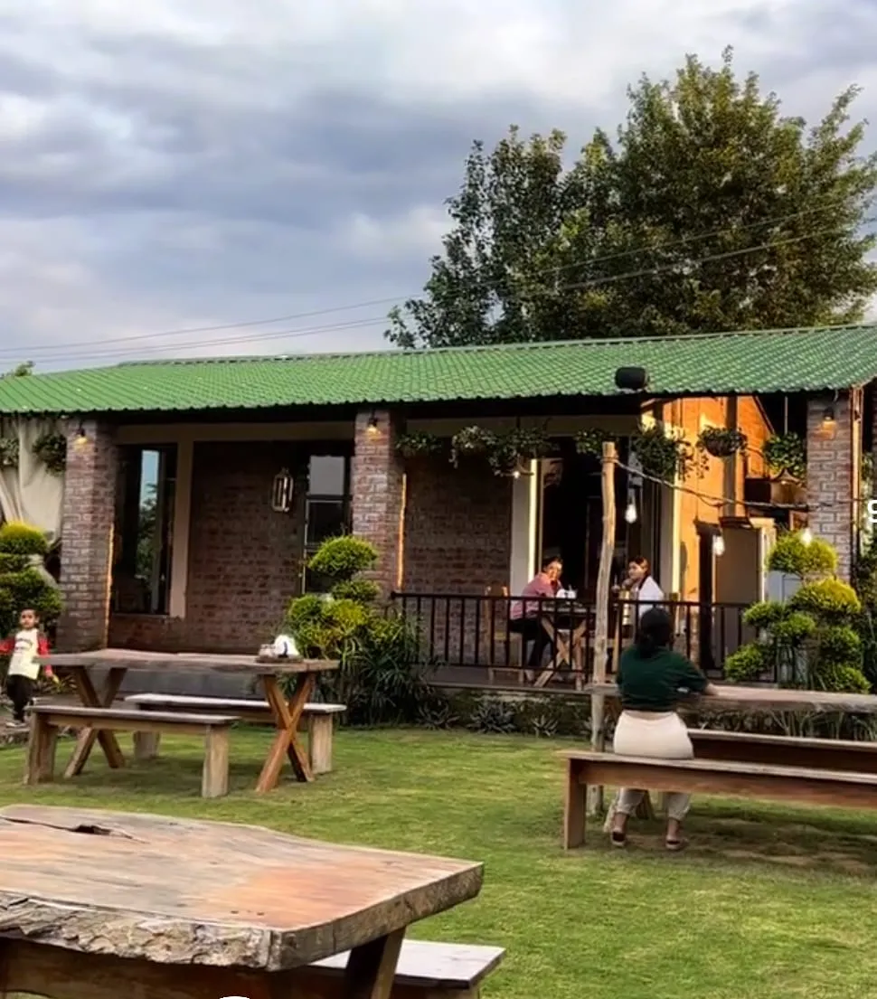 Caffe Cavallo at dusk: wooden picnic benches on the lawn, diners on the lit deck, dramatic sky overhead.