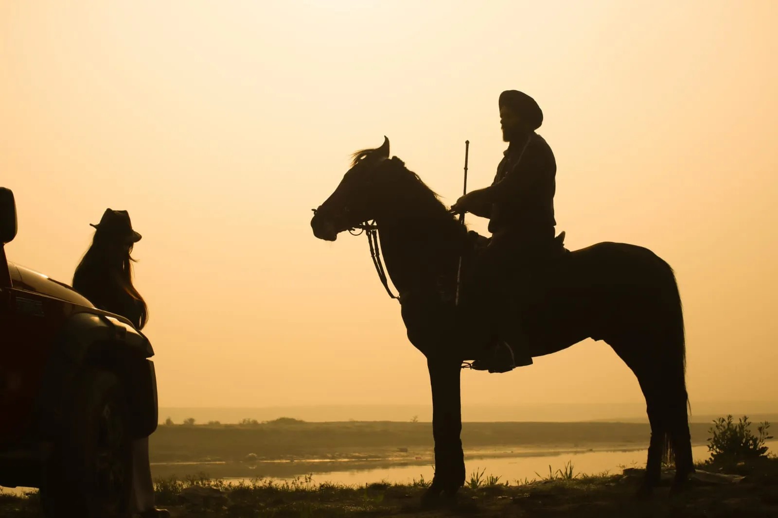A rider silhouetted against a sunset over the river.
